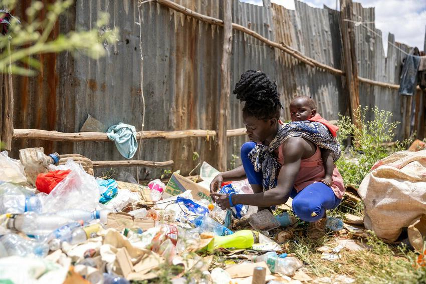 Doreen with her daughter on her back picking up waste.