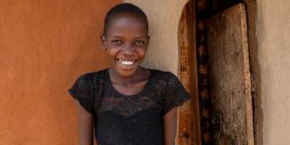 Nakiru stands outside her home smiling