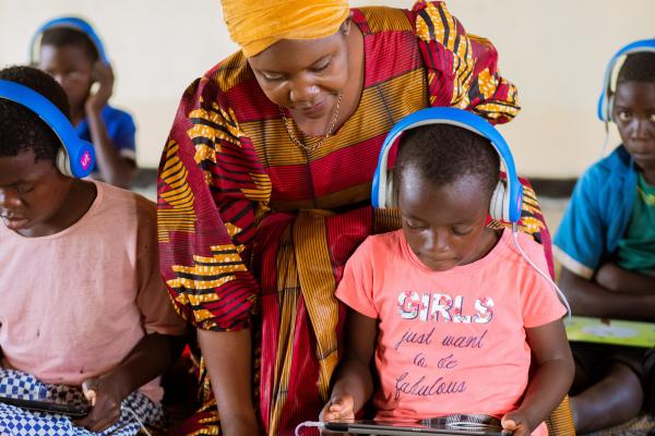 Volunteer helps child with tablet