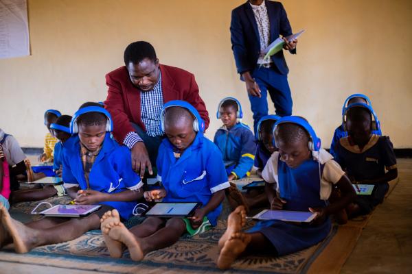 VSO National volunteer, Theonas, helping Thoko use the tablets in the learning centre.