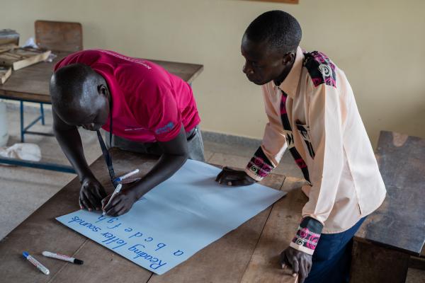 Volunteer Alfred works with teacher Elijah to create some teaching materials