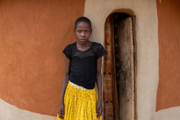 Nakiru stands outside her home