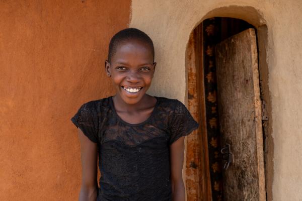 Nakiru stands outside her home smiling
