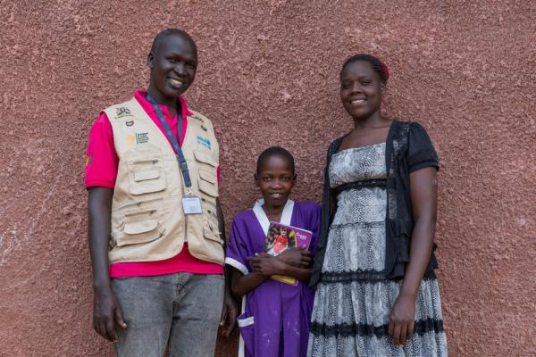 Nakiru stands outside her classroom with volunteer Alfred and teacher Barbra